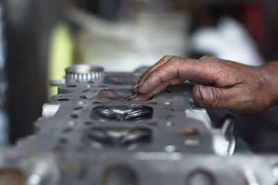 Close-up of mechanic hand on engine at repair shop