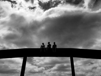 Low angle view of silhouette people standing against sky