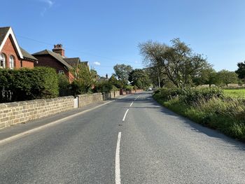 View along, ripley road, with trees, houses, and a blue sky in, nidd, harrogate, uk
