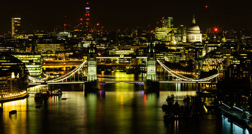 Aerial view of illuminated bridge over river at night