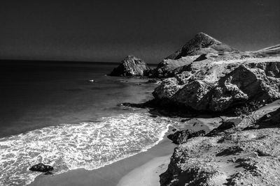 Scenic view of rocks on beach against sky