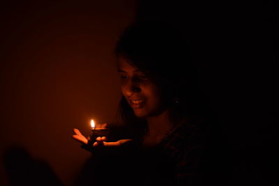 Portrait of man holding lit candle in the dark