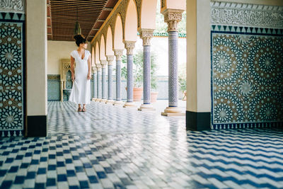 Rear view of woman standing on tiled floor in building