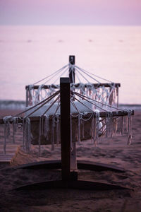 Wicker hammock on sandy beach at sunset