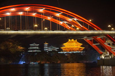 Illuminated bridge over river at night