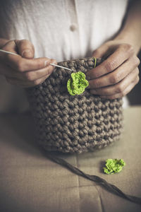 Midsection of woman knitting purse at table