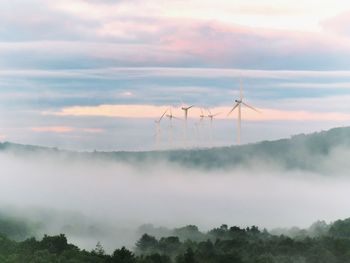 Wind turbines on landscape against sky during sunset