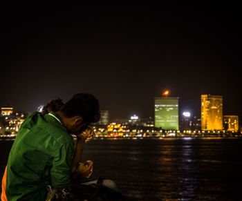 Woman photographing illuminated street light at night