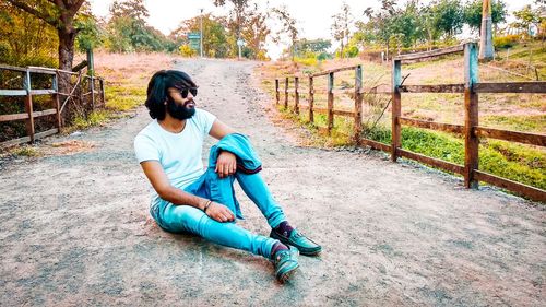 Full length of man siting on dirt road