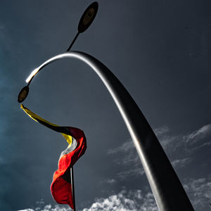 Low angle view of street light against sky with flag