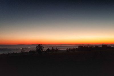 Scenic view of silhouette field against clear sky during sunset