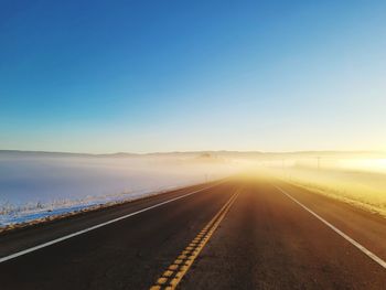 Empty road against clear sky with fog ahead.