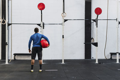 Athlete with medicine ball looking at exercise equipment in gym