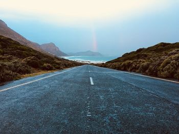 Diminishing perspective of road leading towards sea against sky