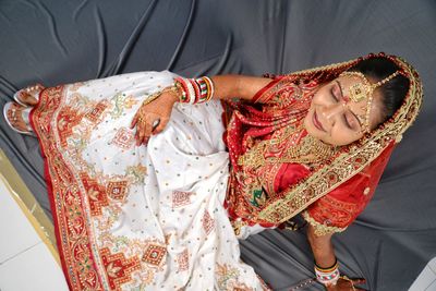 Thoughtful bride sitting on textile 