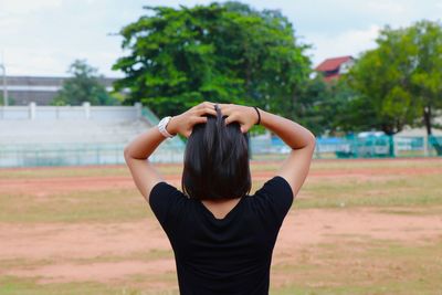 Rear view of woman standing against trees