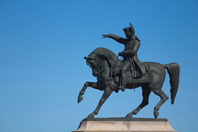 Low angle view of statue against clear blue sky during sunny day