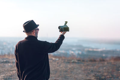 Rear view of man photographing sea against sky