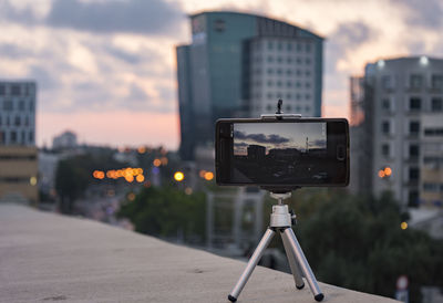 Close-up of camera against sky during sunset