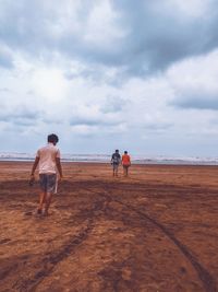 Rear view of people at beach against sky