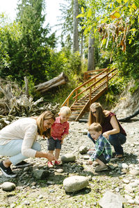 Side view of a family exploring tide pools together on a rocky beach