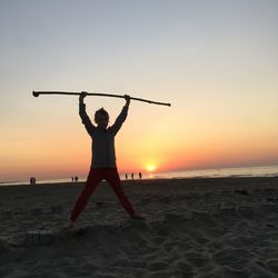 Man on beach against sky during sunset