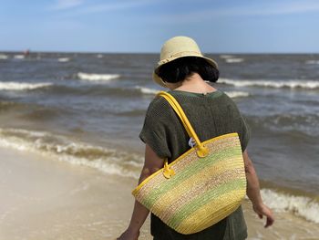 Rear view of woman standing at beach