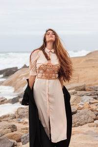 Woman with dress and harness at the beach on a windy day, portugal