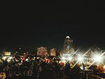 Crowd at illuminated park against clear sky at night