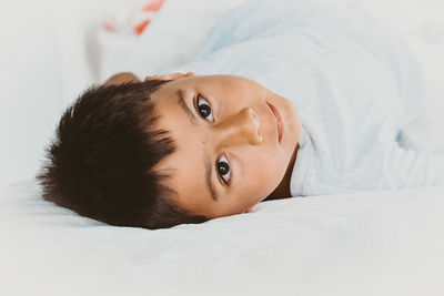 Portrait of young woman lying on bed at home