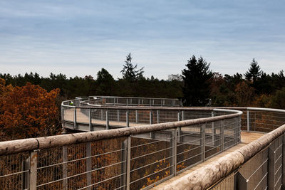 Railing by trees against sky