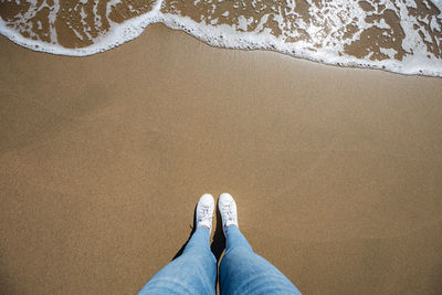 Low section of person standing on sand