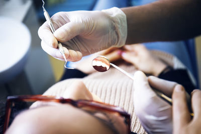 Cropped image of dentist examining patient's teeth in clinic