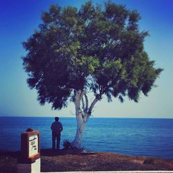 Man standing by tree against sea