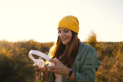 Portrait of young woman with arms raised against sky