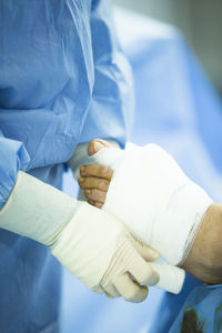 Cropped image of surgeon wrapping bandage on patient wounded foot