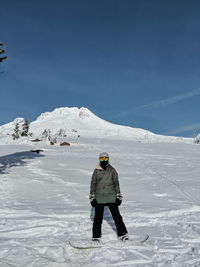 Woman standing on snowcapped mountain against sky