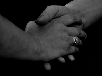 Cropped hands of couple against black background