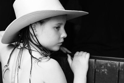 Close-up of girl looking away against black background