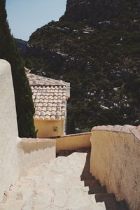 Stone wall by building against sky