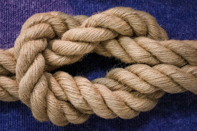 Close-up of rope tied up over blue background