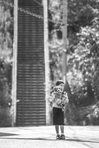 Full length of boy holding dog on street