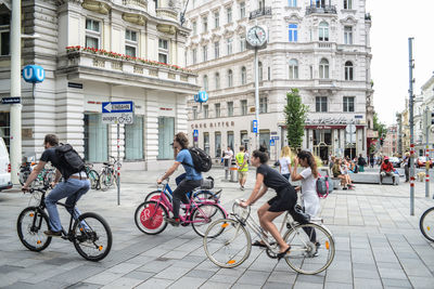 People riding bicycle on street against buildings