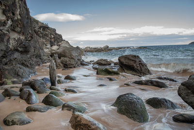 Rocks on beach against sky