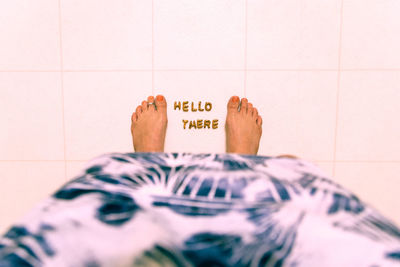 Low section of woman with hello there text on tiled floor