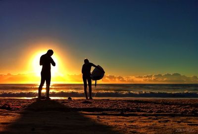 Silhouette of people on beach at sunset