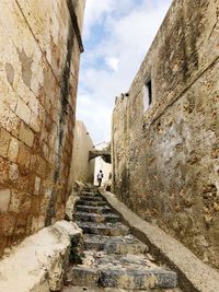 Low angle view of narrow alley amidst buildings against sky