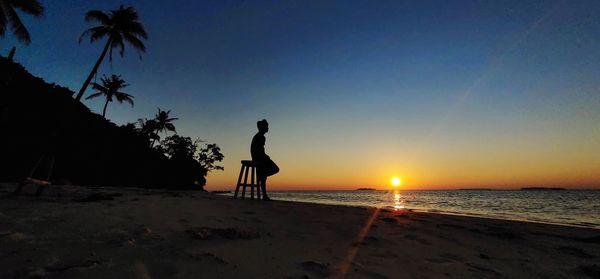 Silhouette person on beach against sky during sunset