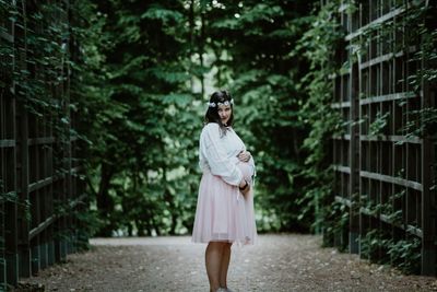 Woman standing by plants against trees