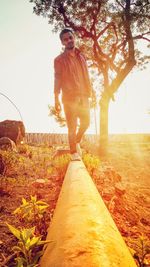 Portrait of young woman standing against tree